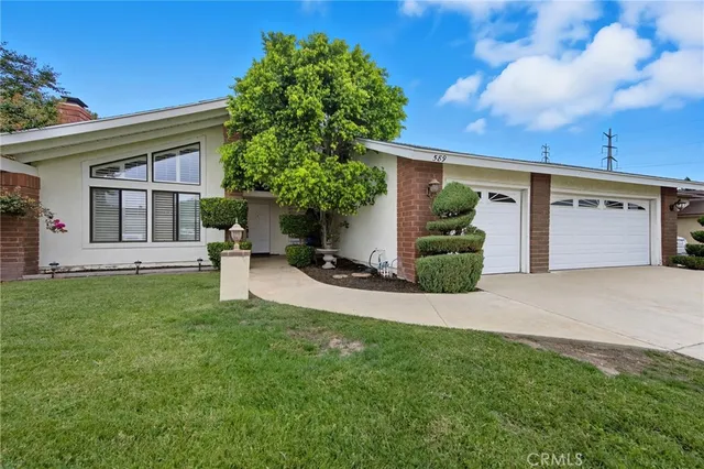 front view of a house with a yard and potted plants
