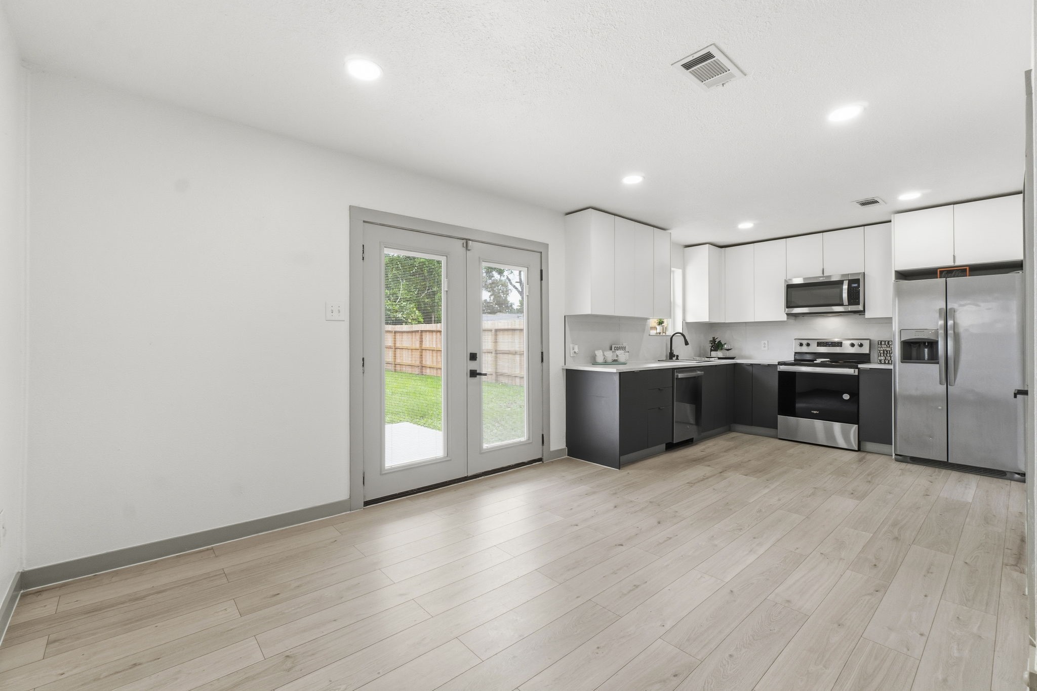 14850 Coaltown Road Willis, TX 77378 - Photo 7 of 41 Bright kitchen and dining area featuring stainless steel appliances, sleek cabinetry, modern finishes, and double doors leading to the backyard.