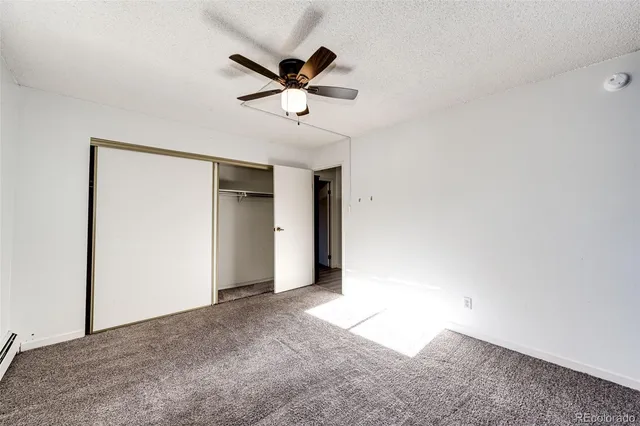 an empty room with chandelier fan and windows