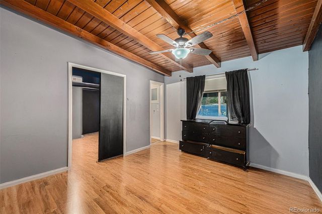 a view of an empty room with wooden floor and a ceiling fan