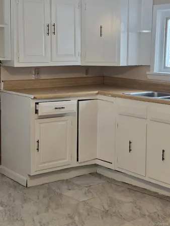 a view of white kitchen with granite countertop cabinets