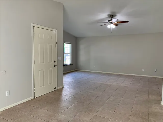 a view of an empty room with chandelier fan