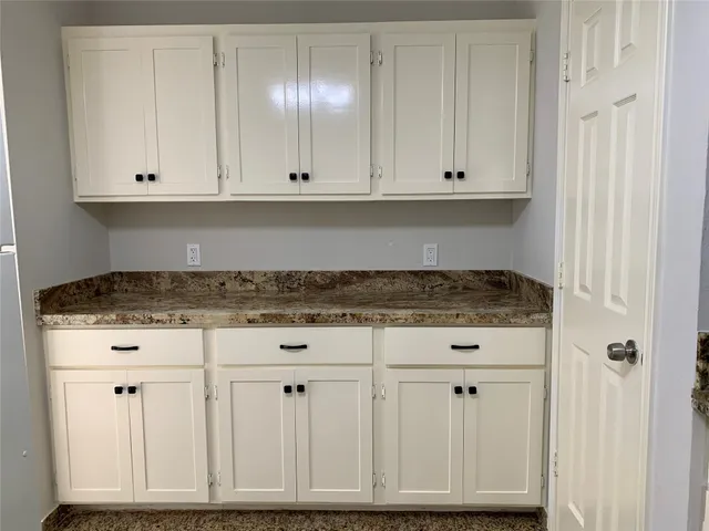 a view of a utility room with white cabinets