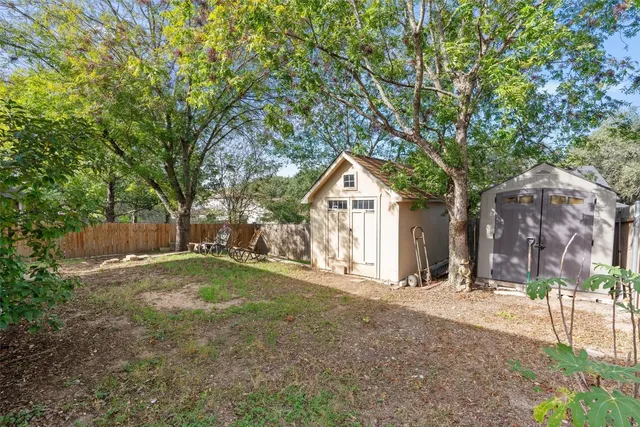 a view of large yard with large trees and wooden fence
