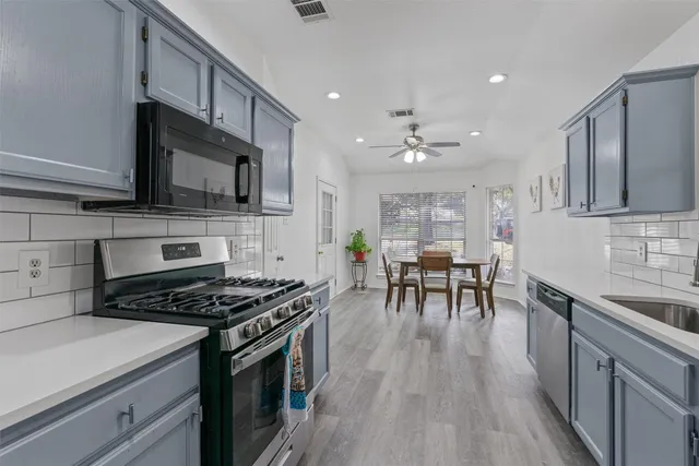 a kitchen with stainless steel appliances a kitchen island hardwood floor sink stove dining table and chairs