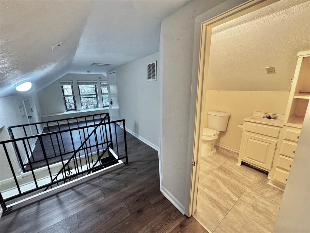 1706 Saddle Road Granbury, TX 76049 - Photo 19 of 29 a view of a hallway with wooden floor and a bathroom