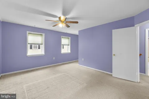 a view of an empty room with chandelier fan and a window