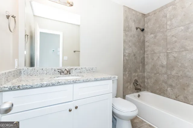 a bathroom with a granite countertop toilet a sink and a bathtub