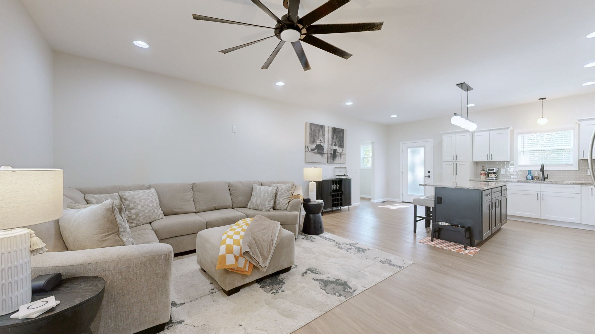 a living room with furniture kitchen view and a wooden floor