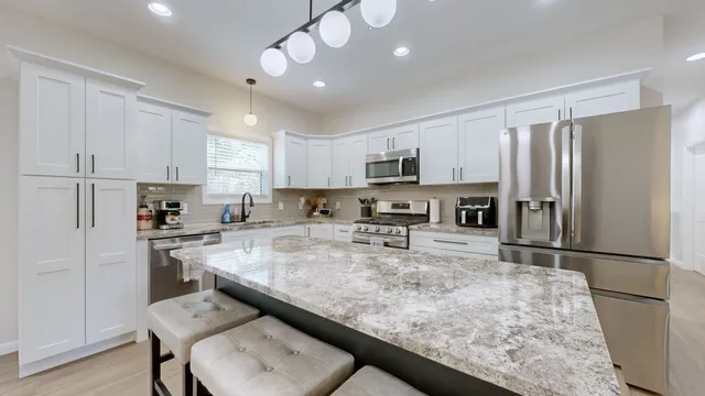 a kitchen with a refrigerator a stove a sink a dining table and chairs