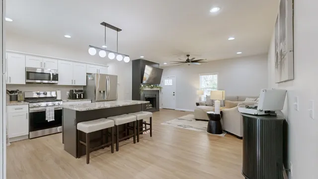 a large white kitchen with lots of counter space dining table and stainless steel appliances