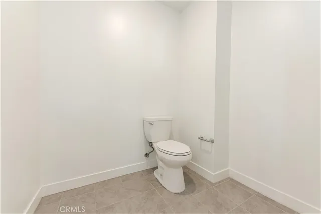 a white toilet sitting next to a white wall