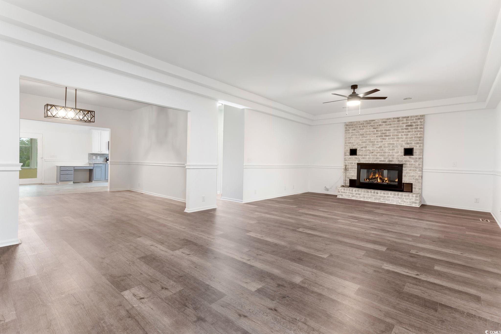 2321 Brick Drive Longs, SC 29568 - Photo 6 of 40 Unfurnished living room with a brick fireplace, wood finished floors, ceiling fan, and a raised ceiling