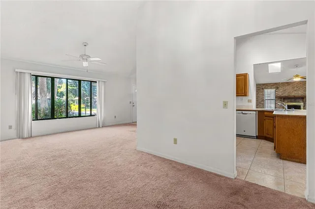 a view of an empty room with kitchen and a window