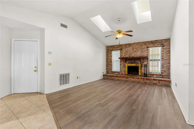an empty room with fireplace cabinet and windows