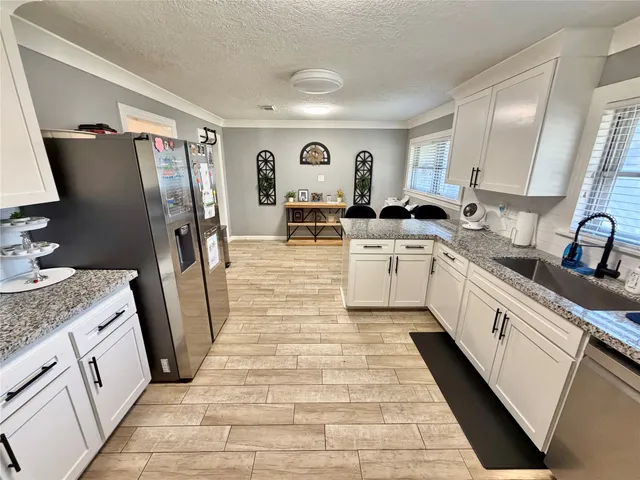 a large white kitchen with cabinets a sink and stainless steel appliances