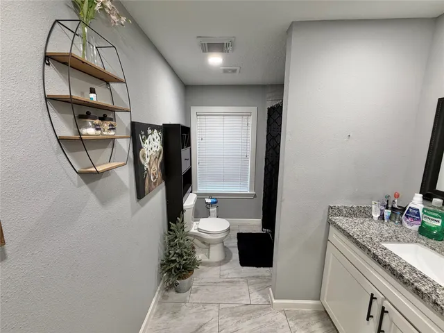 a bathroom with a granite countertop sink a toilet a mirror and vanity