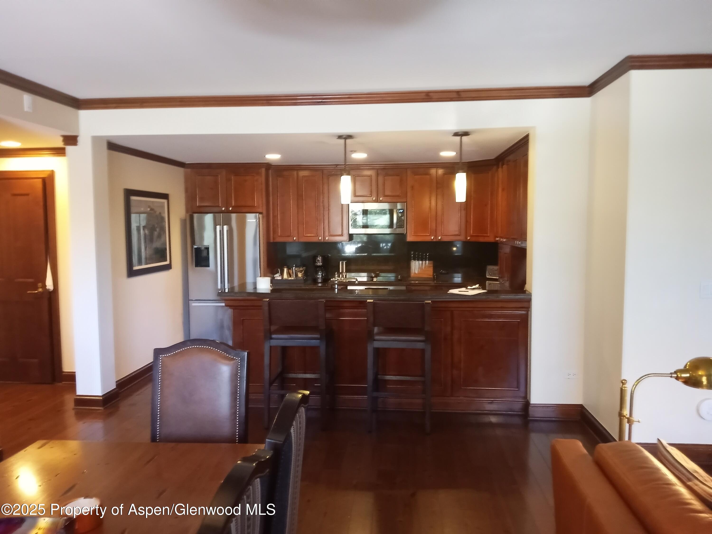 197 Prospector Road, Unit 2312 FIXED WEEKS 1 34 35 Aspen, CO 81611 - Photo 34 of 38 a kitchen with stainless steel appliances granite countertop a refrigerator a stove a sink a dining table and chairs with wooden floor