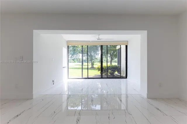 a view of an empty room with wooden floor and a large window