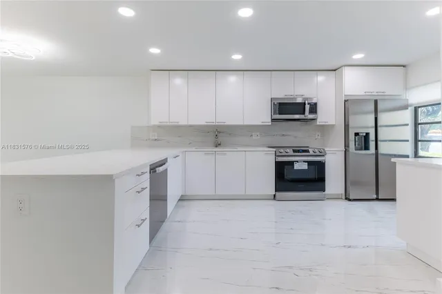 a large kitchen with cabinets a sink a window and stainless steel appliances