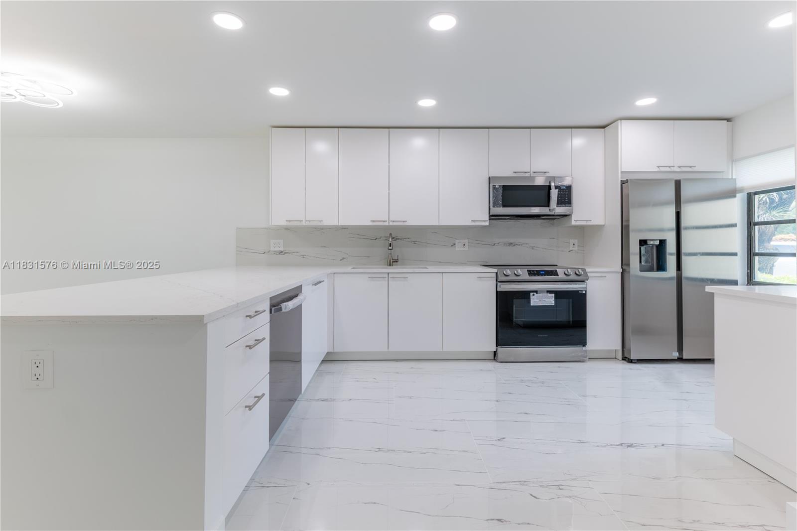 8435 Casa Del Lago, Unit 22C Boca Raton, FL 33433 - Photo 2 of 55 a large kitchen with cabinets a sink a window and stainless steel appliances