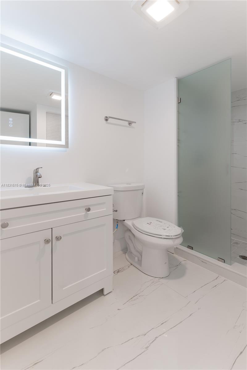 8435 Casa Del Lago, Unit 22C Boca Raton, FL 33433 - Photo 34 of 55 a bathroom with a toilet a sink a mirror and vanity