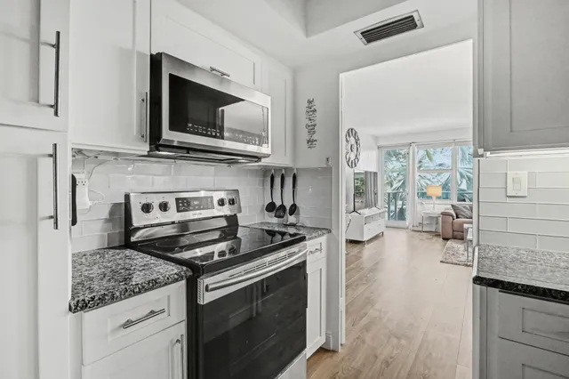a kitchen with stainless steel appliances granite countertop a stove a sink and a microwave