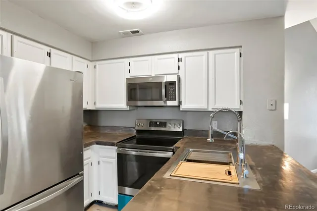 a kitchen with stainless steel appliances granite countertop a refrigerator a stove and a microwave