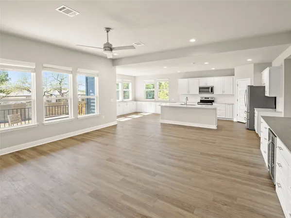 a large kitchen with stainless steel appliances a large counter top a wooden floor a fireplace and a window