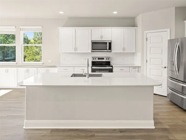 a large kitchen with stainless steel appliances granite countertop a lot of counter space and wooden floors