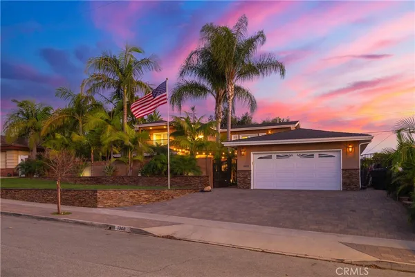 a view of a house with a yard and palm trees