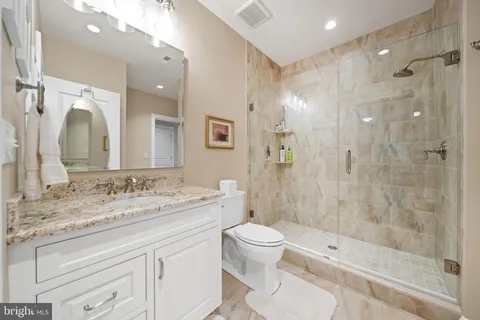 a spacious bathroom with a granite countertop sink a toilet and a mirror