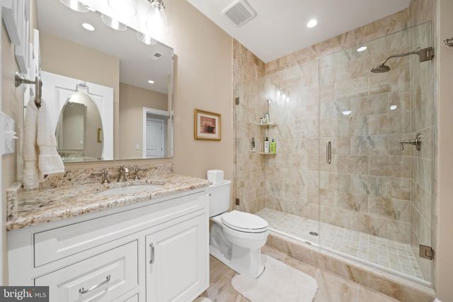 a spacious bathroom with a granite countertop sink a toilet and a mirror