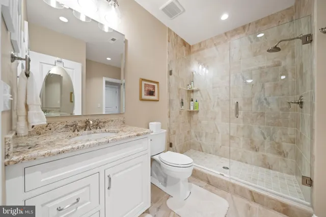 a spacious bathroom with a granite countertop sink a toilet and a mirror
