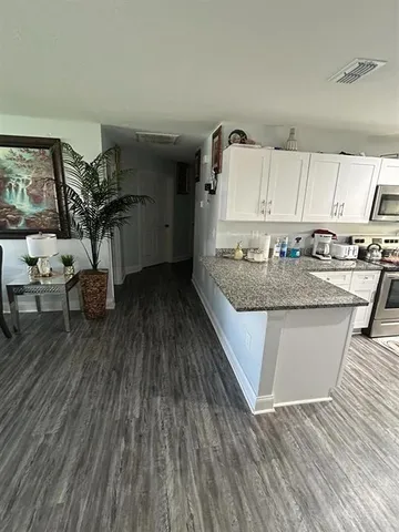 a kitchen with a sink a stove cabinets and wooden floor