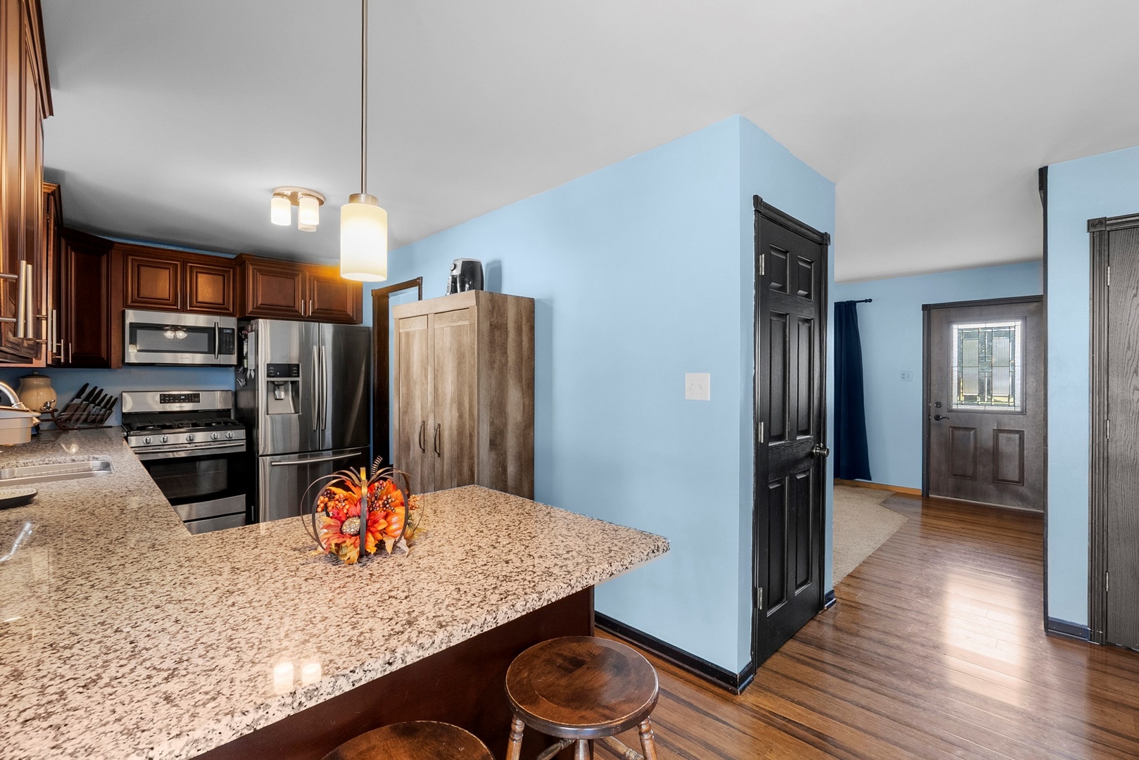 808 Stonegate Road New Lenox, IL 60451 - Photo 5 of 24 a kitchen with stainless steel appliances kitchen island granite countertop a refrigerator a stove and oven with wooden floor