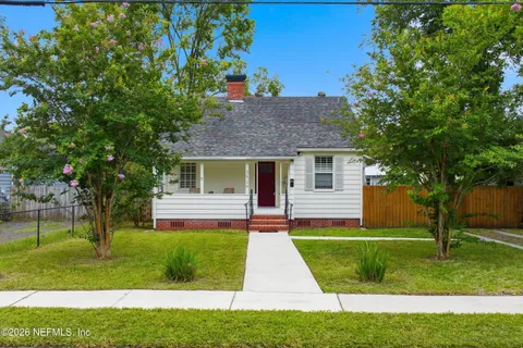 a front view of a house with a yard and tree
