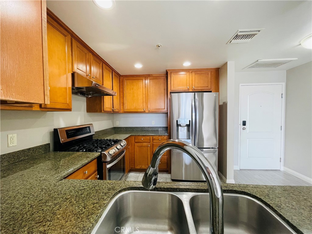 6800 Corbin Avenue Reseda, CA 91335 - Photo 8 of 37 a kitchen with stainless steel appliances granite countertop a sink a refrigerator and a stove top oven with wooden floor