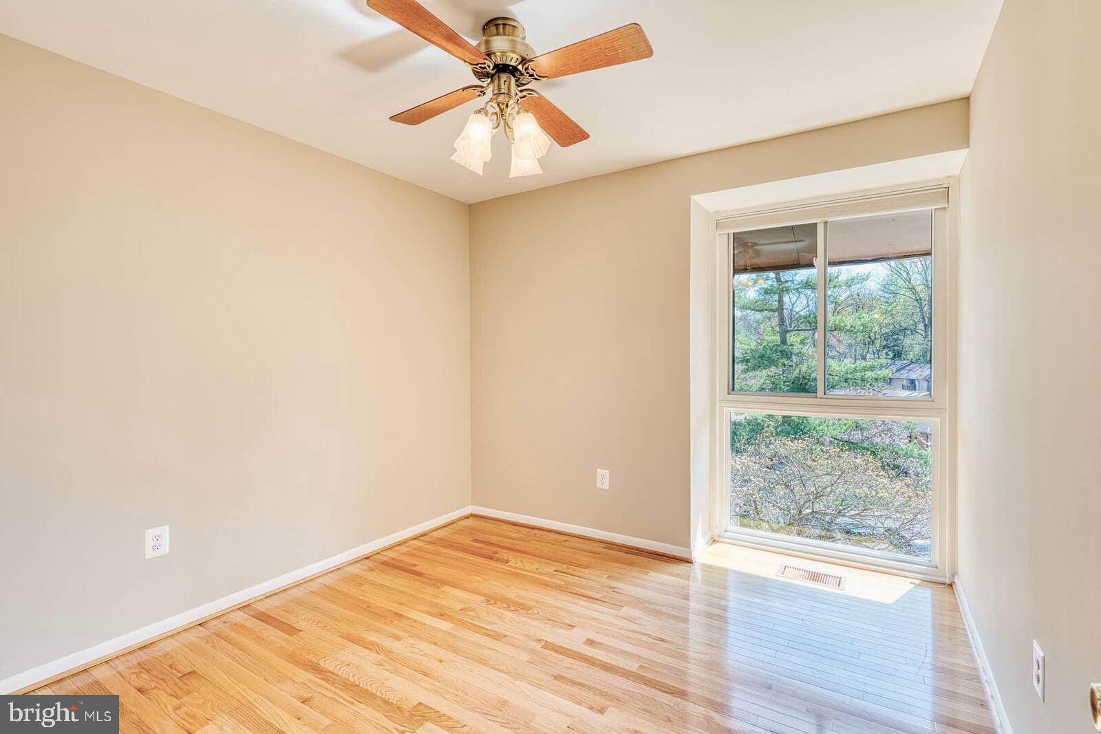 9238 Three Oaks Drive Silver Spring, MD 20901 - Photo 26 of 42 an empty room with wooden floor fan and windows