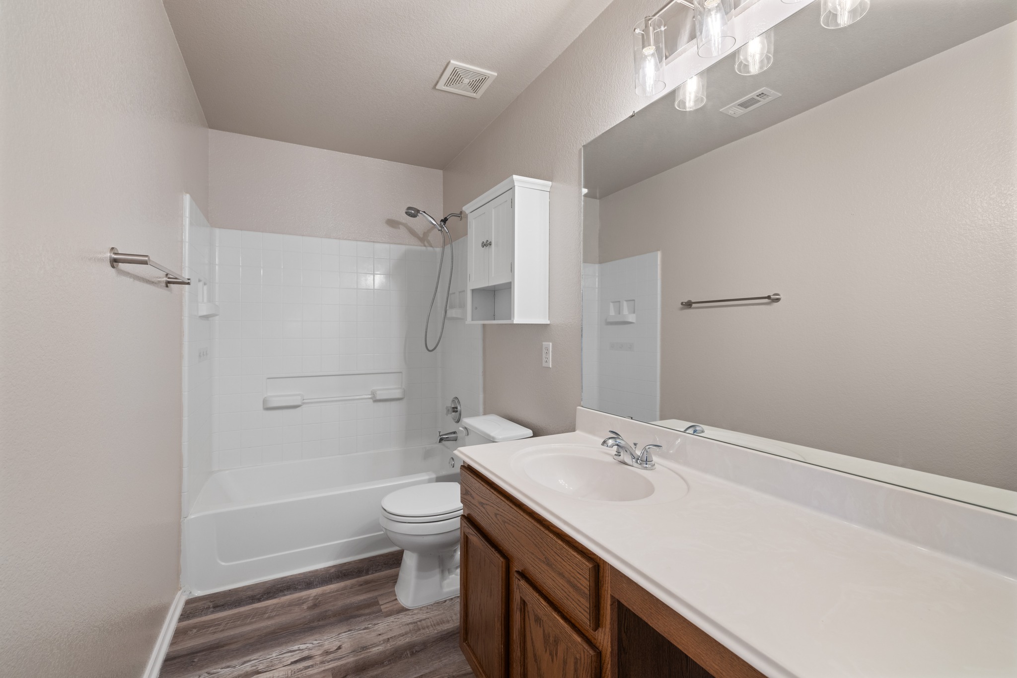 403 Red Hawk Drive Leander, TX 78641 - Photo 23 of 37 Bathroom featuring wood-finish flooring, a full vanity with a single basin sink, and a combination tub and shower with white tile surround
