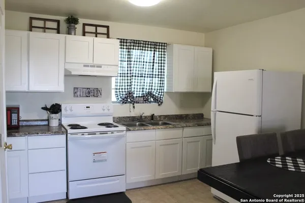a kitchen with a sink a stove a refrigerator and cabinets