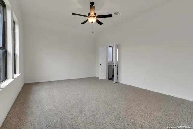 an empty room with a ceiling fan and a window