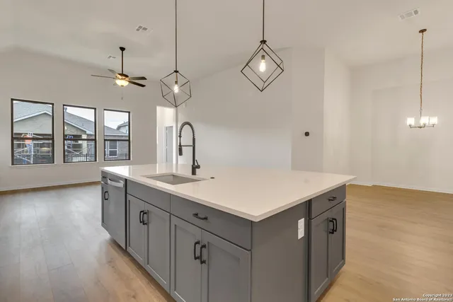 a kitchen with a sink a chandelier stainless steel appliances and cabinets