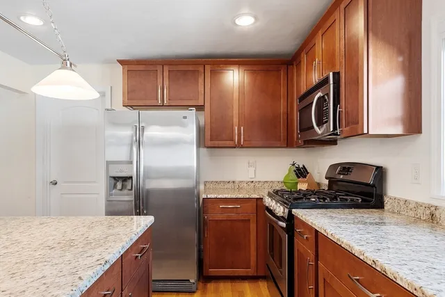 a kitchen with stainless steel appliances granite countertop a refrigerator a sink and wooden cabinets