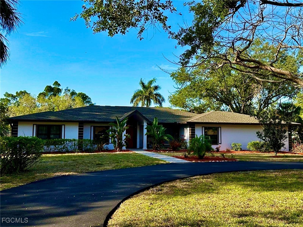3644 Putter Point Lane Fort Myers, FL 33919 - Photo 4 of 50 a view of house in front of a big yard with potted plants and large trees