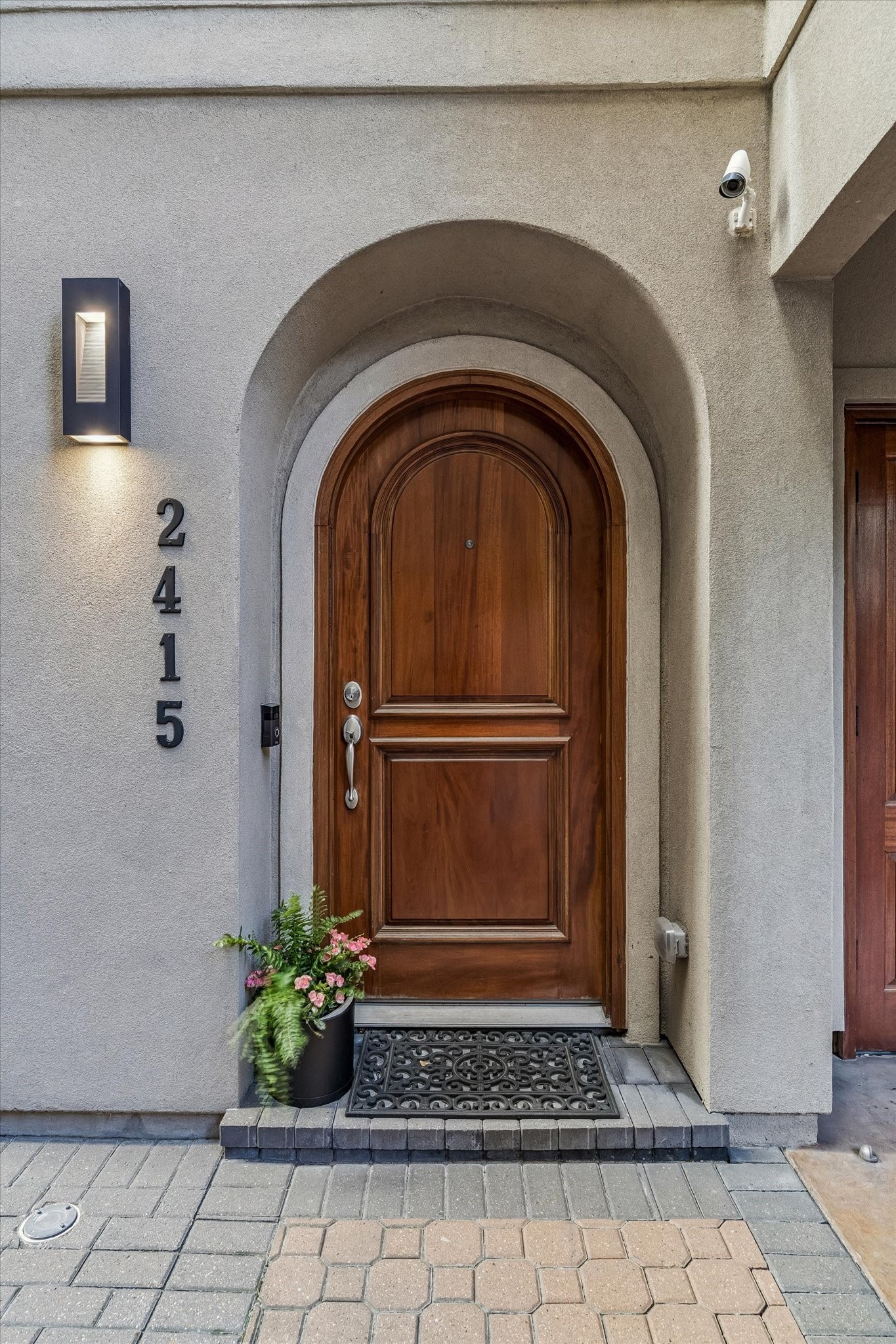 2415 West Main Street Houston, TX 77098 - Photo 11 of 48 Refined stucco exterior with composition roof, enhanced by a modern security system and landscape lighting. Set on a north–south corner lot, the home captures balanced light and standout curb appeal.