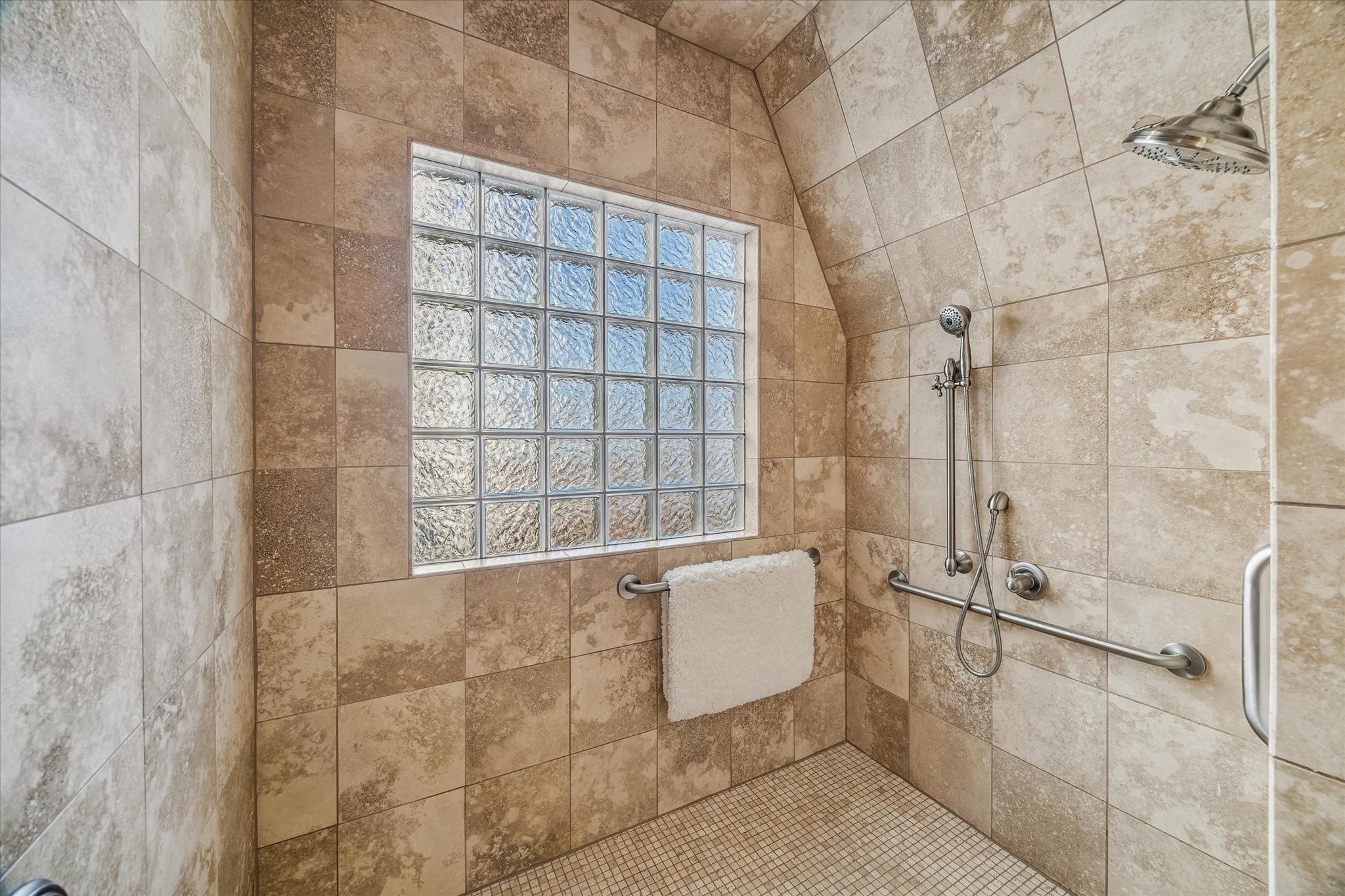 2415 West Main Street Houston, TX 77098 - Photo 36 of 48 The spa-inspired walk-in wet room offers a serene retreat, complete with multiple shower heads, rich travertine flooring and surround, and a glass-brick privacy window that brings in soft, natural light while maintaining discretion.