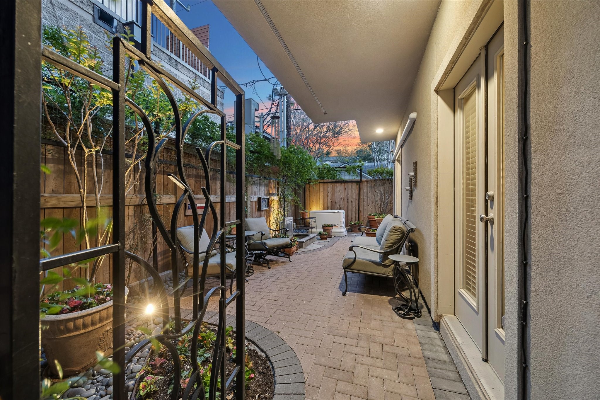 2415 West Main Street Houston, TX 77098 - Photo 41 of 48 The spacious patio, with custom wrought iron gate, finished with elegant brick pavers, acts as a private sanctuary ideal for hosting gatherings or enjoying peaceful moments surrounded by curated landscaping.