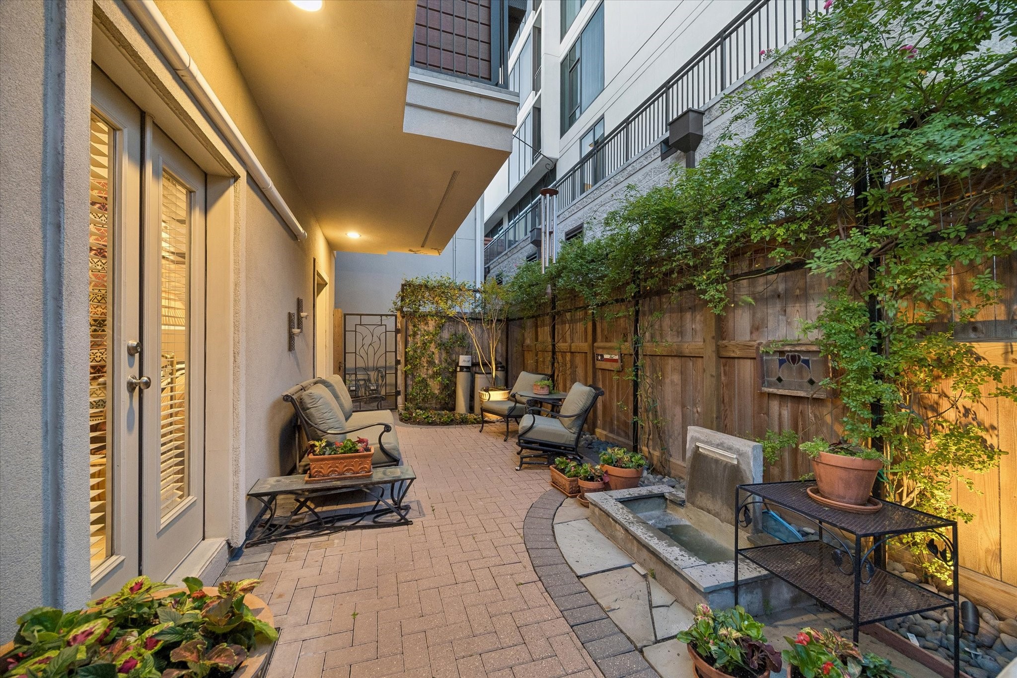 2415 West Main Street Houston, TX 77098 - Photo 43 of 48 This additional view captures the peaceful ambiance of the brick-paver patio, framed by a graceful wrought-iron gate and complemented by a tranquil water feature—an inviting setting perfect for quiet relaxation or elegant outdoor entertaining.