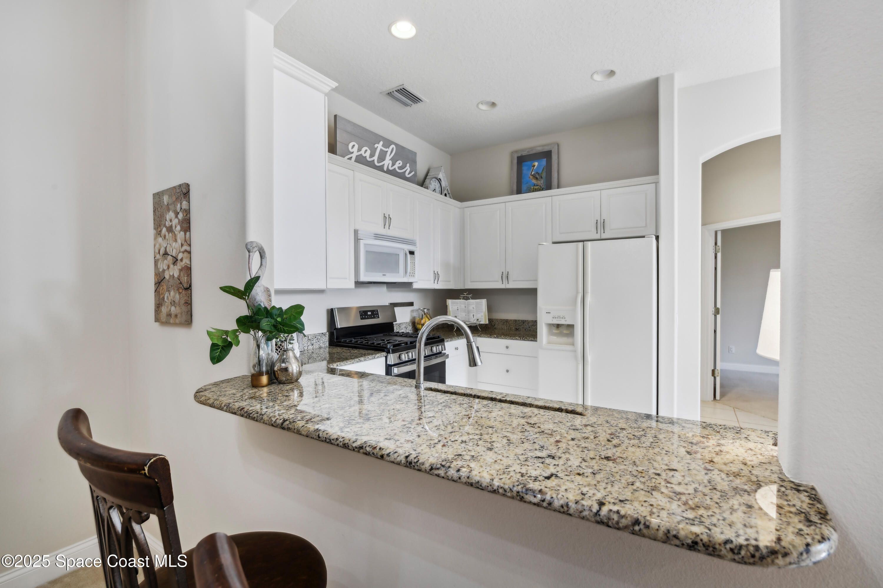 4040 Alamanda Key Drive Melbourne, FL 32901 - Photo 8 of 46 a kitchen with granite countertop a sink chairs and cabinets
